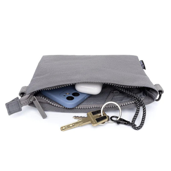 Interior del bolso pequeño color gris con llaves, móvil y airpods hecho de plástico reciclado de la marca española Lefrik