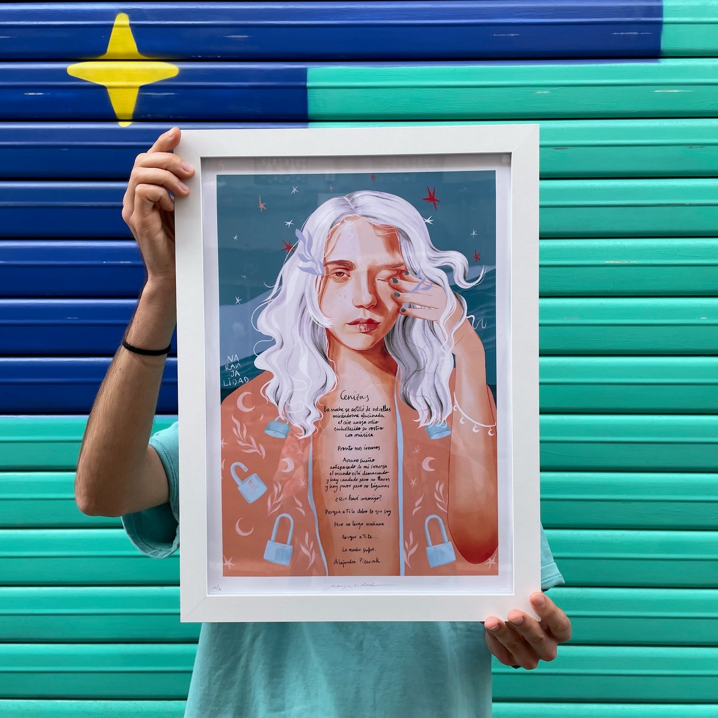 Una persona sostiene un marco de color blanco para fotos o prints con una lámina de Naranjalidad