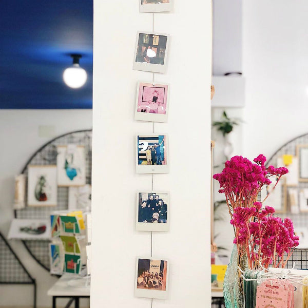 Cable metálico con fotografías Polaroid colgadas con imanes en la tienda de regalos Gnomo de Valencia