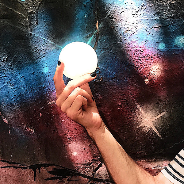 Lámpara con forma de luna pequeña sobre fondo graffiti de galaxia
