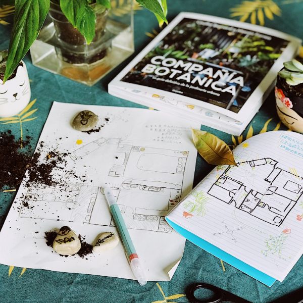 Libro para aprender a cuidar plantas en una mesa con tierra y un plano de una casa