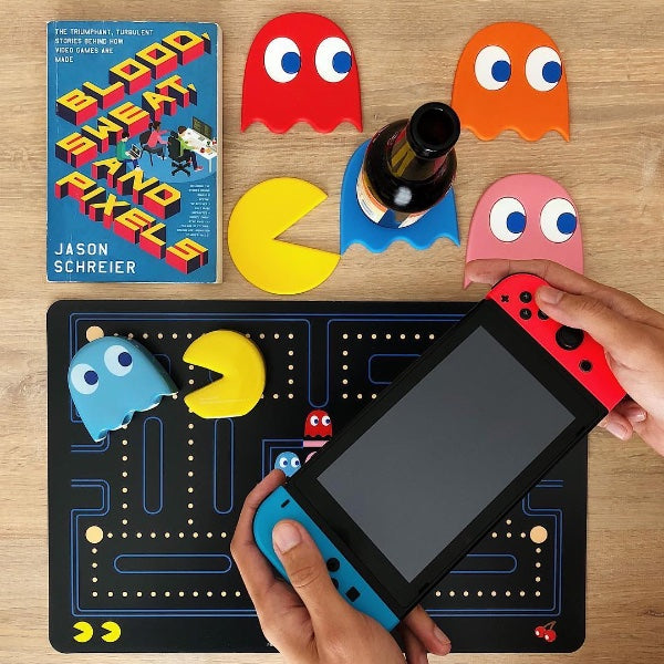 Chico con videoconsola  apoya una cerveza sobre un posavasos de pacman azul