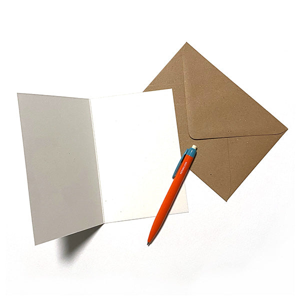 Tarjeta en blanco abierta con sobre craft y bolígrafo naranja