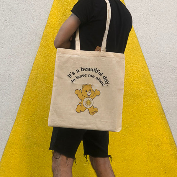 Bolsa de tela con el texto It's a beautiful day to leave me alone y un oso amoroso amarillo