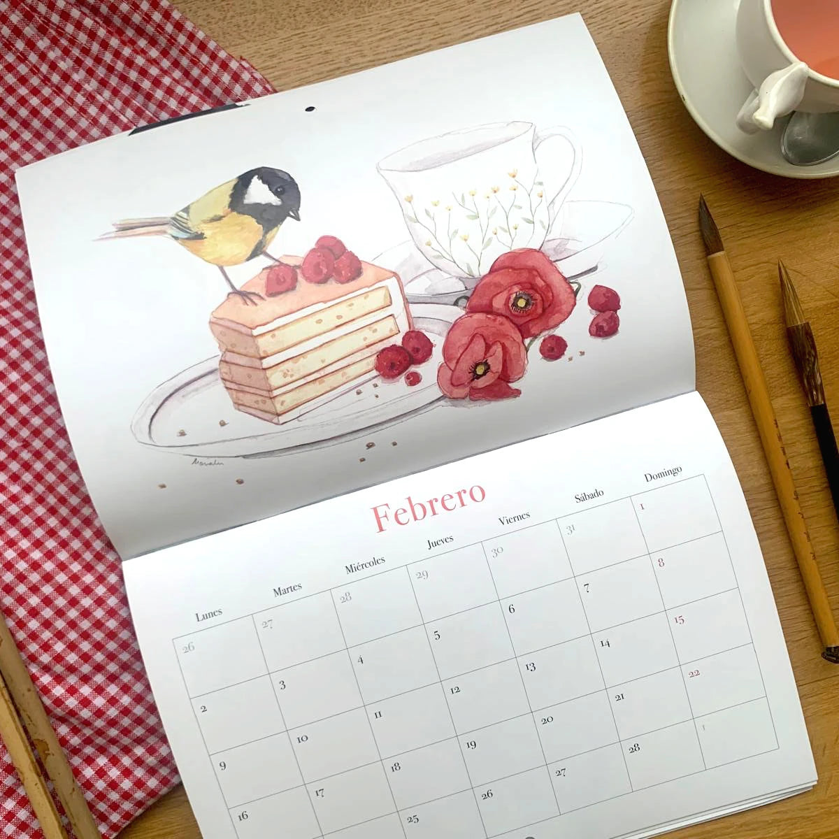 Diseño del mes de febrero del Calendario de pared 2026 de Esther Gili, Marialu Gili y Lady Desidia con ilustración de Marialu Gili de un pajarillo sobre un trozo de pastel de frambuesas