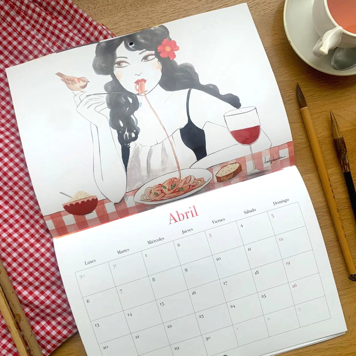 Diseño del mes de marzo del Calendario de pared 2026 de Esther Gili, Marialu Gili y Lady Desidia con ilustración de Lady Desidia de una chica comiendo espaguettis