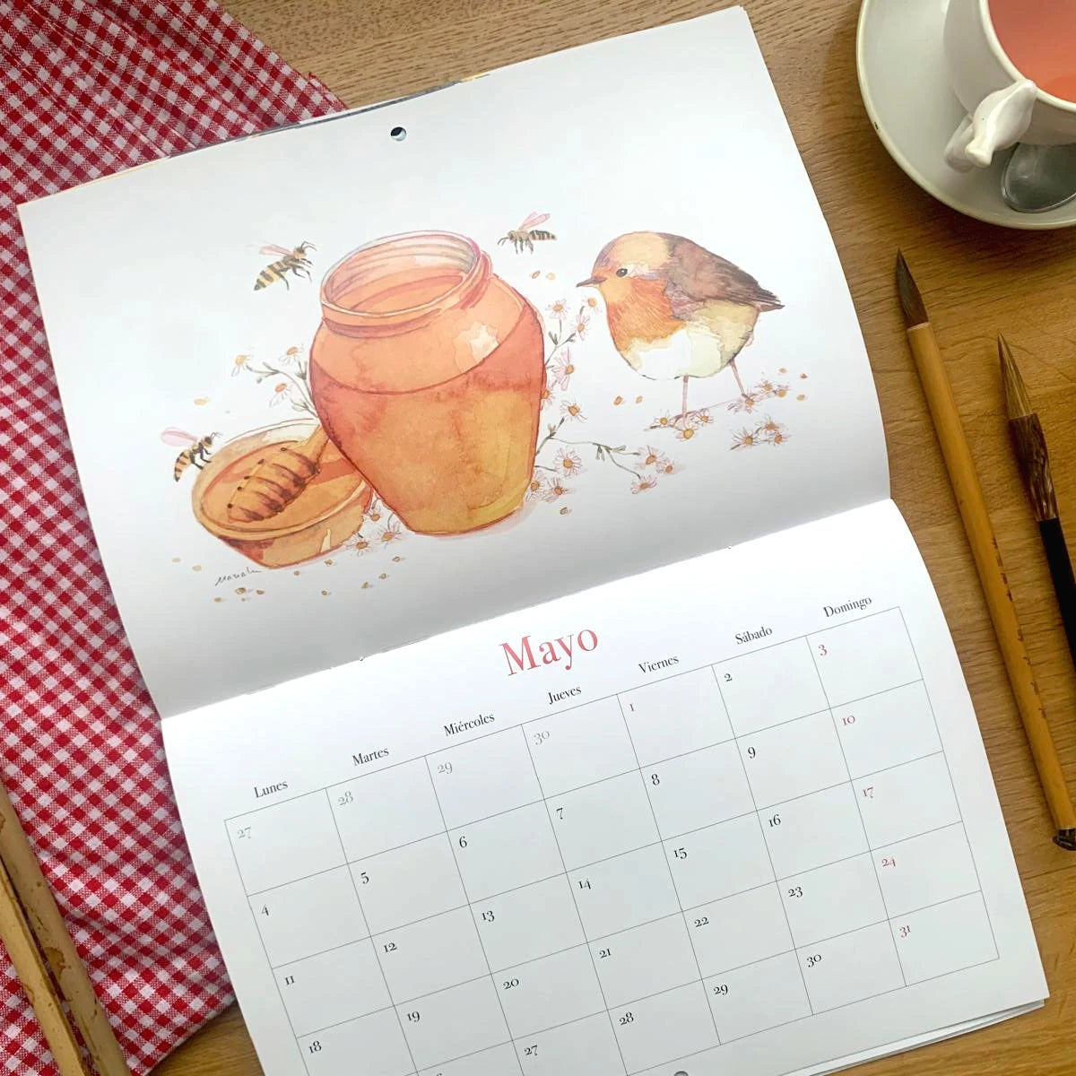 Diseño del mes de mayo del Calendario de pared 2026 de Esther Gili, Marialu Gili y Lady Desidia con ilustración de Marialu Gili de un pájaro y unas abejas junto a un bote de miel