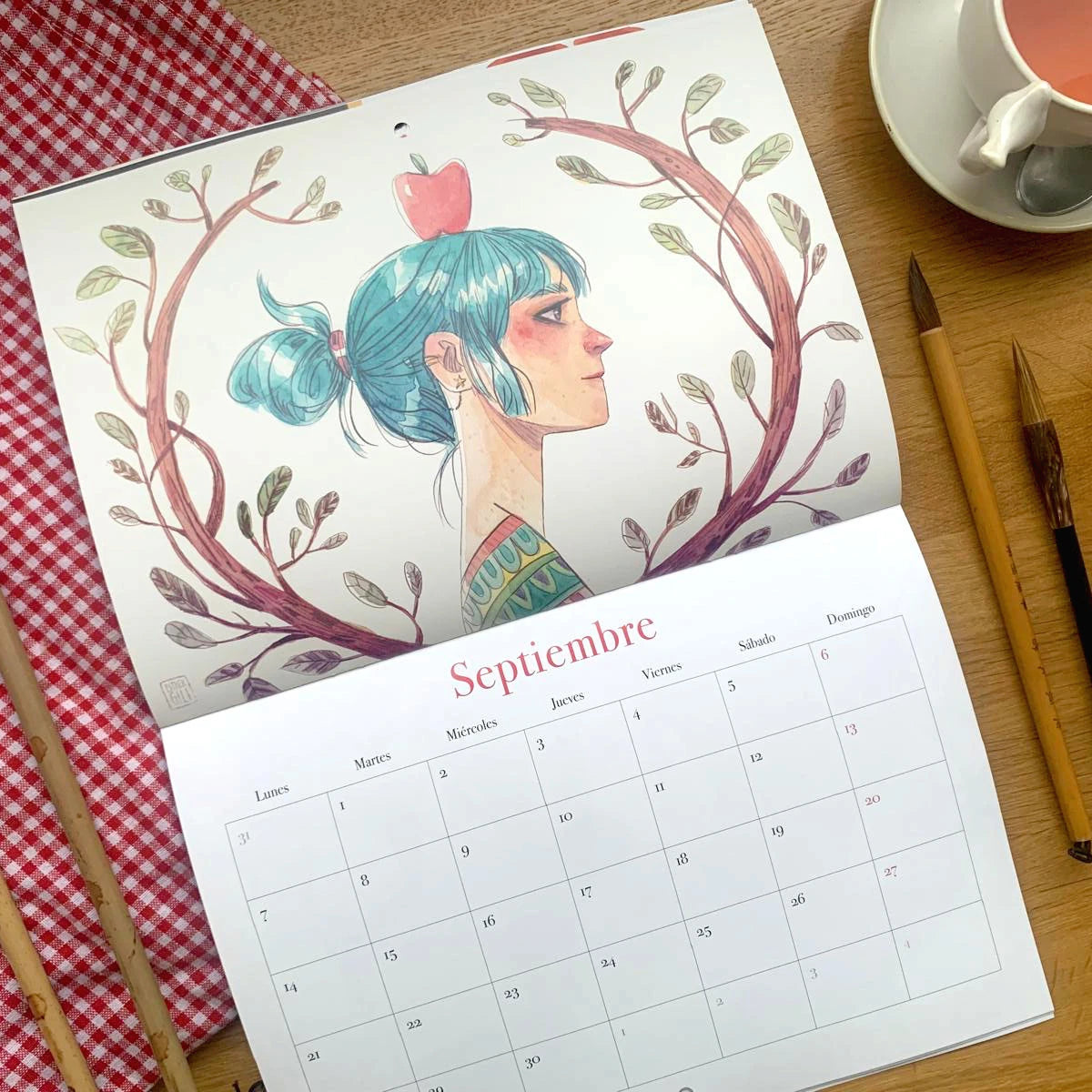 Diseño del mes de septiembre del Calendario de pared 2026 de Esther Gili, Marialu Gili y Lady Desidia con ilustración de Esther Gili de una chica de perfil con el pelo azul y una manzana en la cabeza