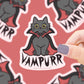 Pegatina con forma de gato adorable con capa de vampiro y colmillitos