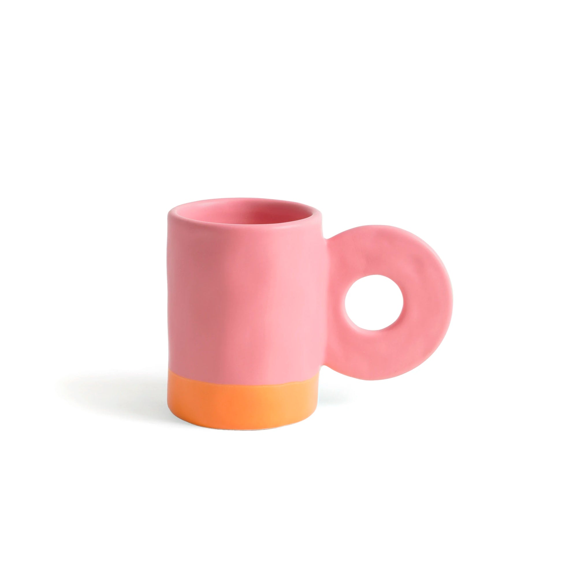 taza de cerámica de color rosa de Helio Ferretti con la base de color naranja, con asa grande en forma de círculo 