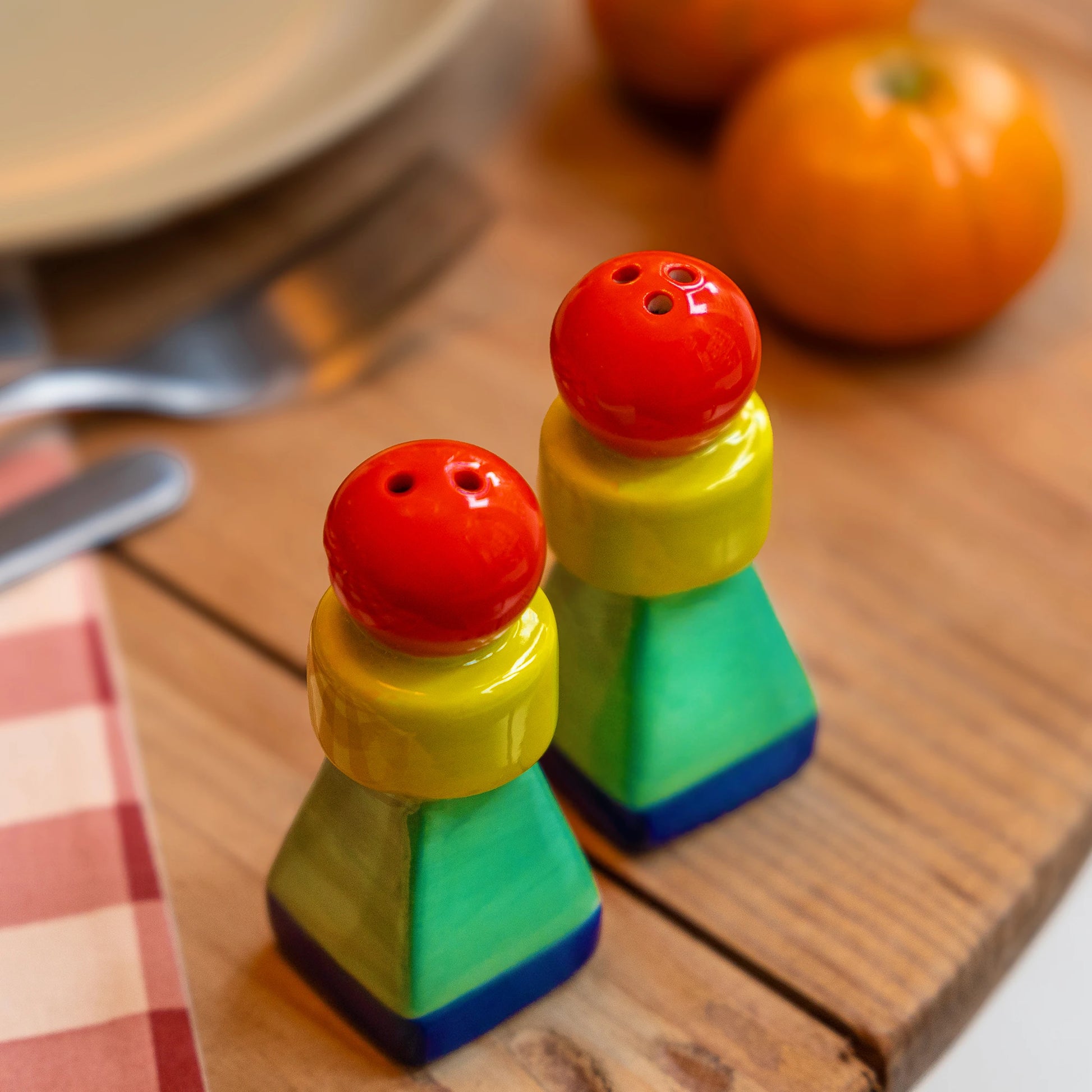 set de salero y pimentero en forma geométrica con una esfera roja, un cilindro amarillo y una pirámide en color verde con la base azul