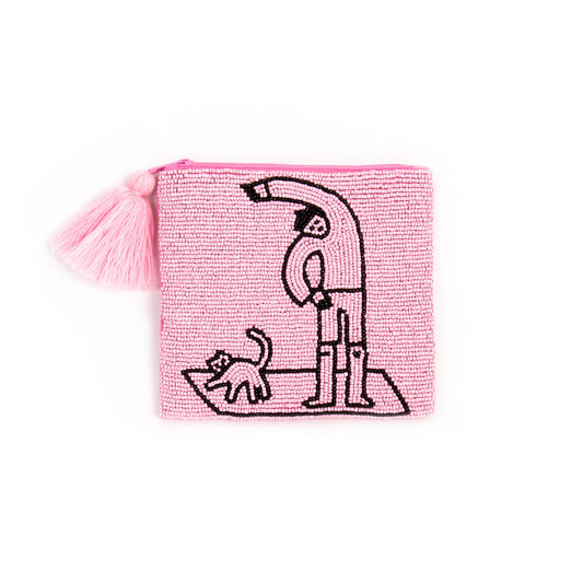 clutch mediano hecho de cuentas de color rosa con un dibujo de una persona haciendo yoga y un gato al lado en cuentas de color negro. y con una borla de color rosa anclada al cierre de la cremallera