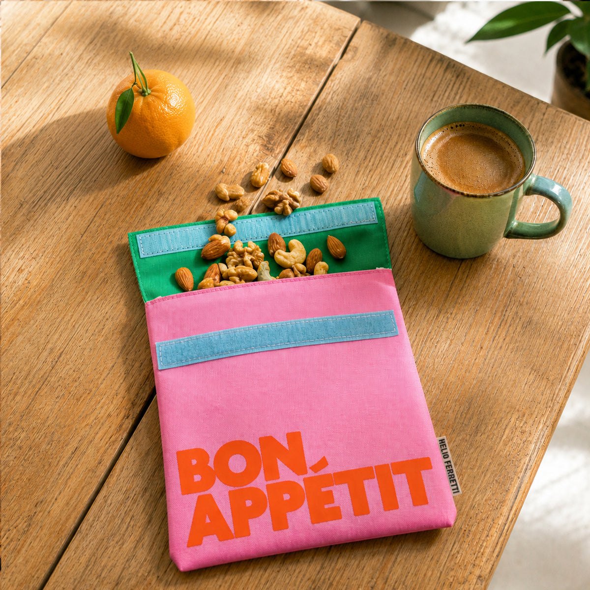 Bolsa de almuerzo Bon Appétit rosa de Helio Ferretti abierta, con frutos secos y cierre de velcro azul.
