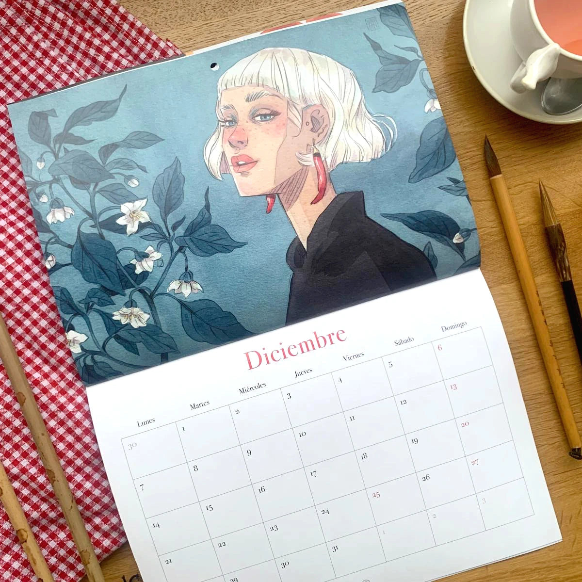 Diseño del mes de diciembre del Calendario de pared 2026 de Esther Gili, Marialu Gili y Lady Desidia con ilustración de Esther Gili de una chica  con el pelo blanco y pendientes de guindilla