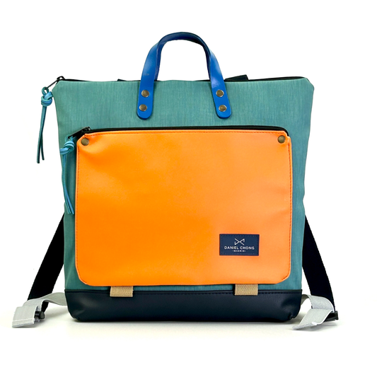 parte delantera de la mochila cuadrada book holder impermeable de color turquesa y naranja de daniel chong