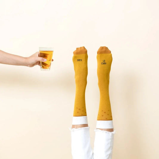 Pies con los calcetines Eres la Caña junto a un vaso de cerveza