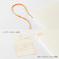 Accesorios incluidos con la agenda Midori MD 2027: marcapáginas de seda naranja y etiquetas de índice con diseño de biblioteca