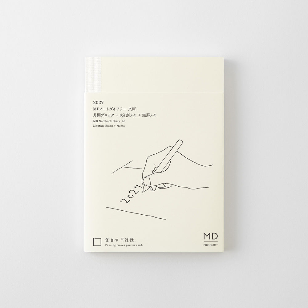 Agenda Midori MD 2027 A6 con funda de plástico transparente mostrando la portada ilustrada con una mano escribiendo "2027"