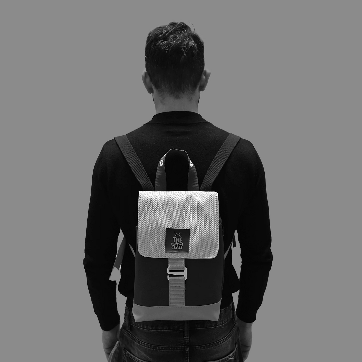 modelo de espaldas con una camiseta negra y vaqueros llevando puesta la mochila de daniel chong the hook mini