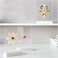 soporte de madera para fotos con la base en color blanco y un doble panel acrílico transparente, con flores prensadas colocadas en el interior