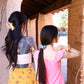 Dos chicas de pelo largo de espaldas, na con una coleta con un scrunchie y otra con una pinza de pelo con forma de perro salchicha