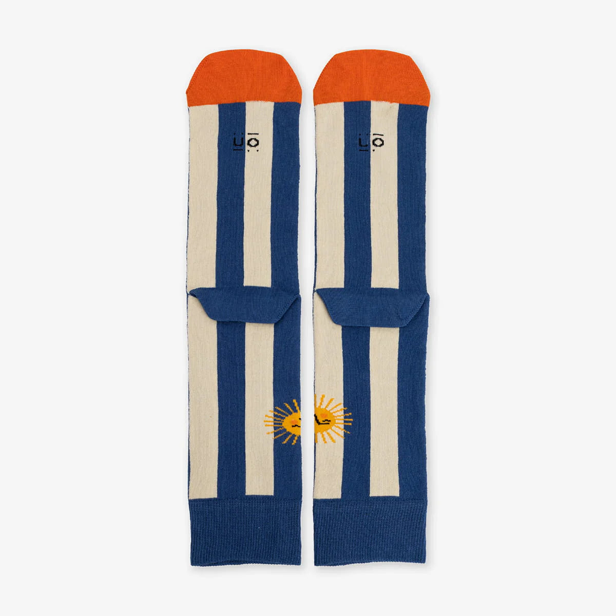Parte de atrás de los calcetines a rayas verticales azules y puntera naranja con dibujo de un sol y el texto "Necesito vacaciones"