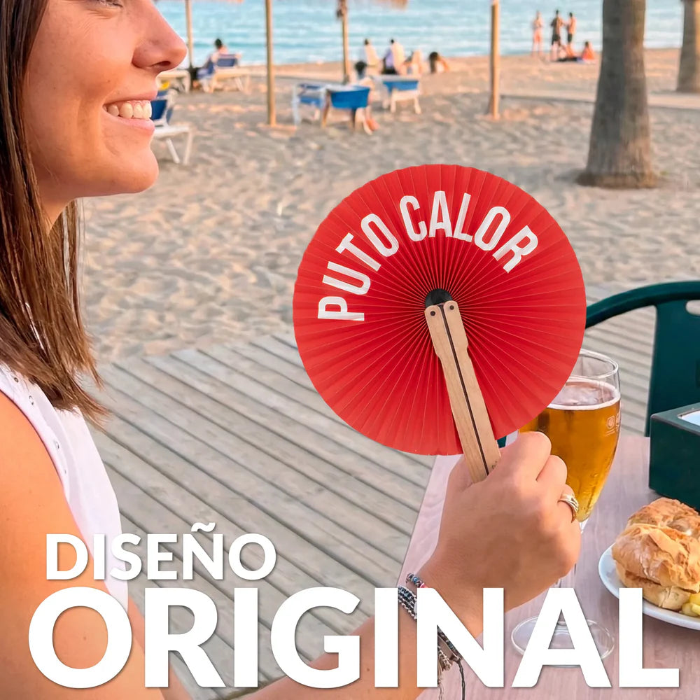 Chica sujetando el paipai plegable redondo de papel en color rojo y con el texto PUTO CALOR en blanco en la playa y con el texto DISEÑO ORIGINAL en blanco