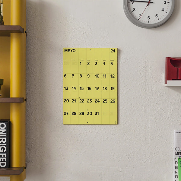 Calendario de pared 2024 a mes vista en papel amarillo tamaño A3 de Colla Paper en una pared de oficina con gotelé