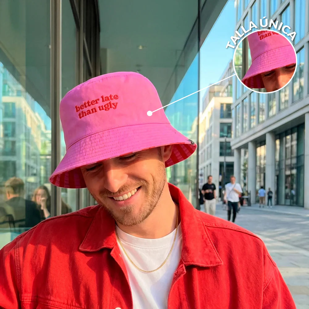modelo con el gorro de Fisura reversible en color rosa  y el texto better late than ugly en color rojo