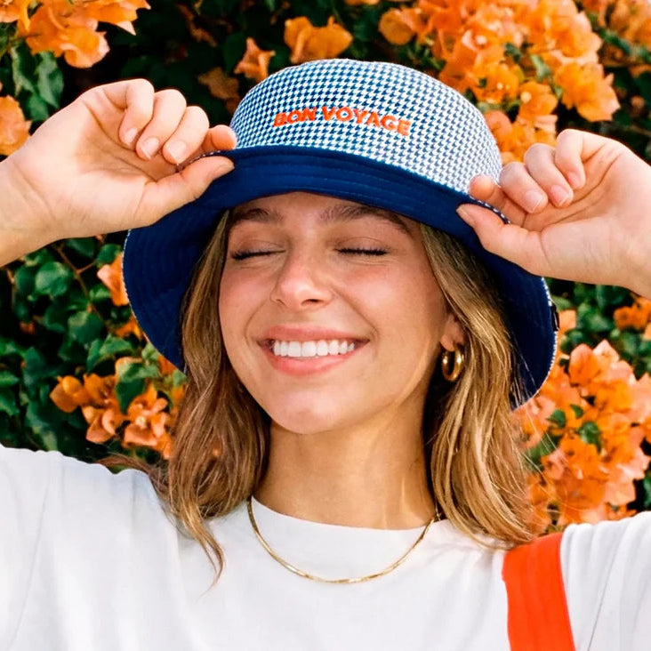 chica con el gorro de Fisura reversible a cuadros azul marino y blanco y el texto BON VOYAGE en color naranja
