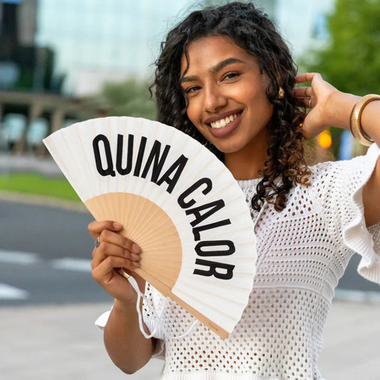 chica sujetando el abanico de fisura en color blanco de tela y madera con el texto en negro "QUINA CALOR" abierto