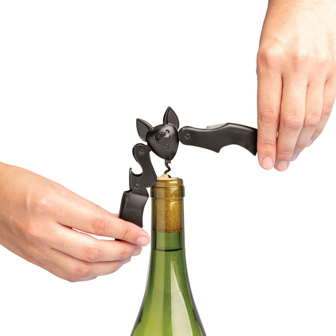 Manos utilizando las alas articuladas del sacacorchos Murciélago de Ototo para extraer el corcho de una botella de vino.