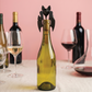 Sacacorchos Murciélago de Ototo colocado sobre una botella de vino blanco, con copas y otras botellas al fondo.