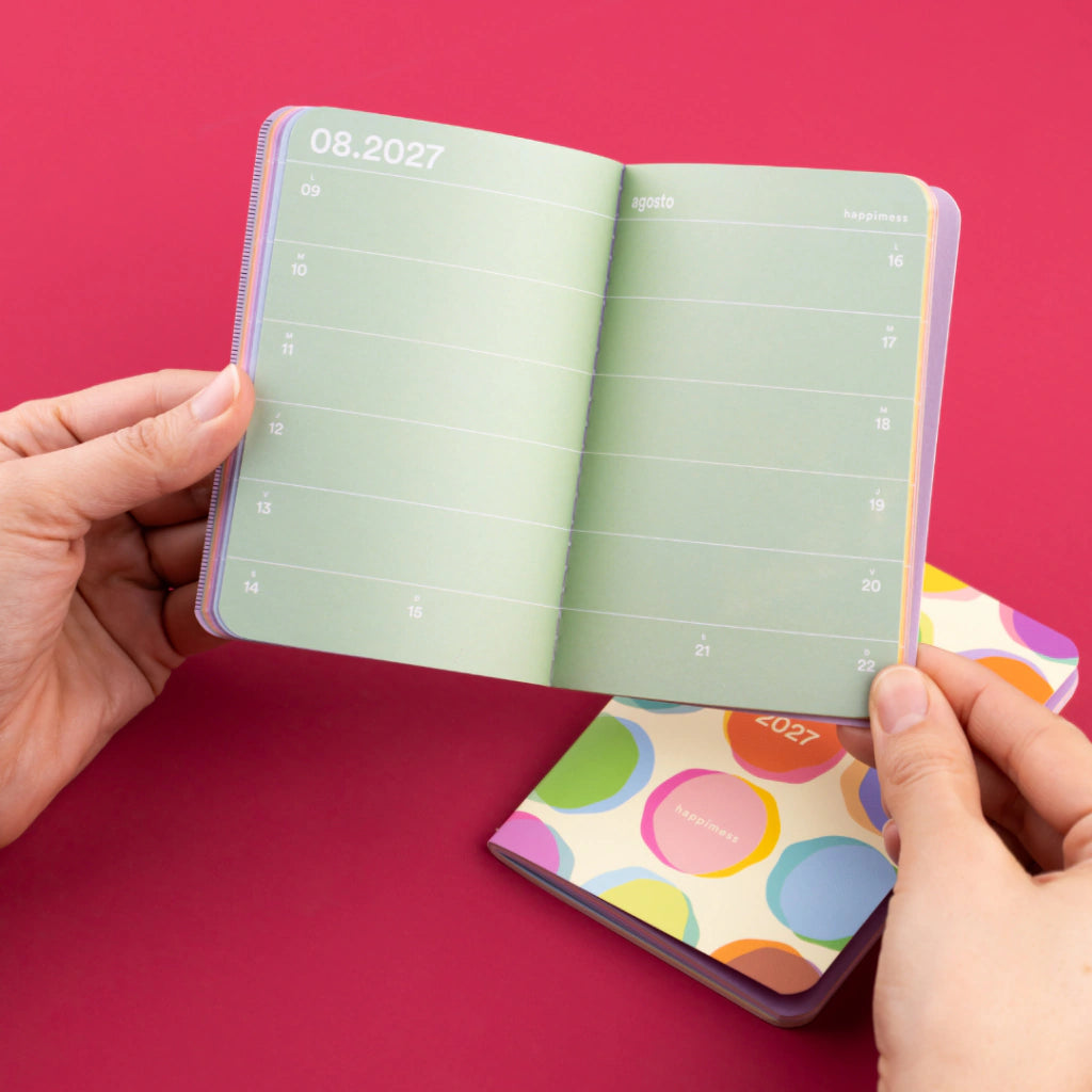 persona sujetando una agenda confetti happimess de monoblock abierta por un spread semanal