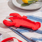 Alhajero en forma de langosta roja sobre una mesa y paño azul. 