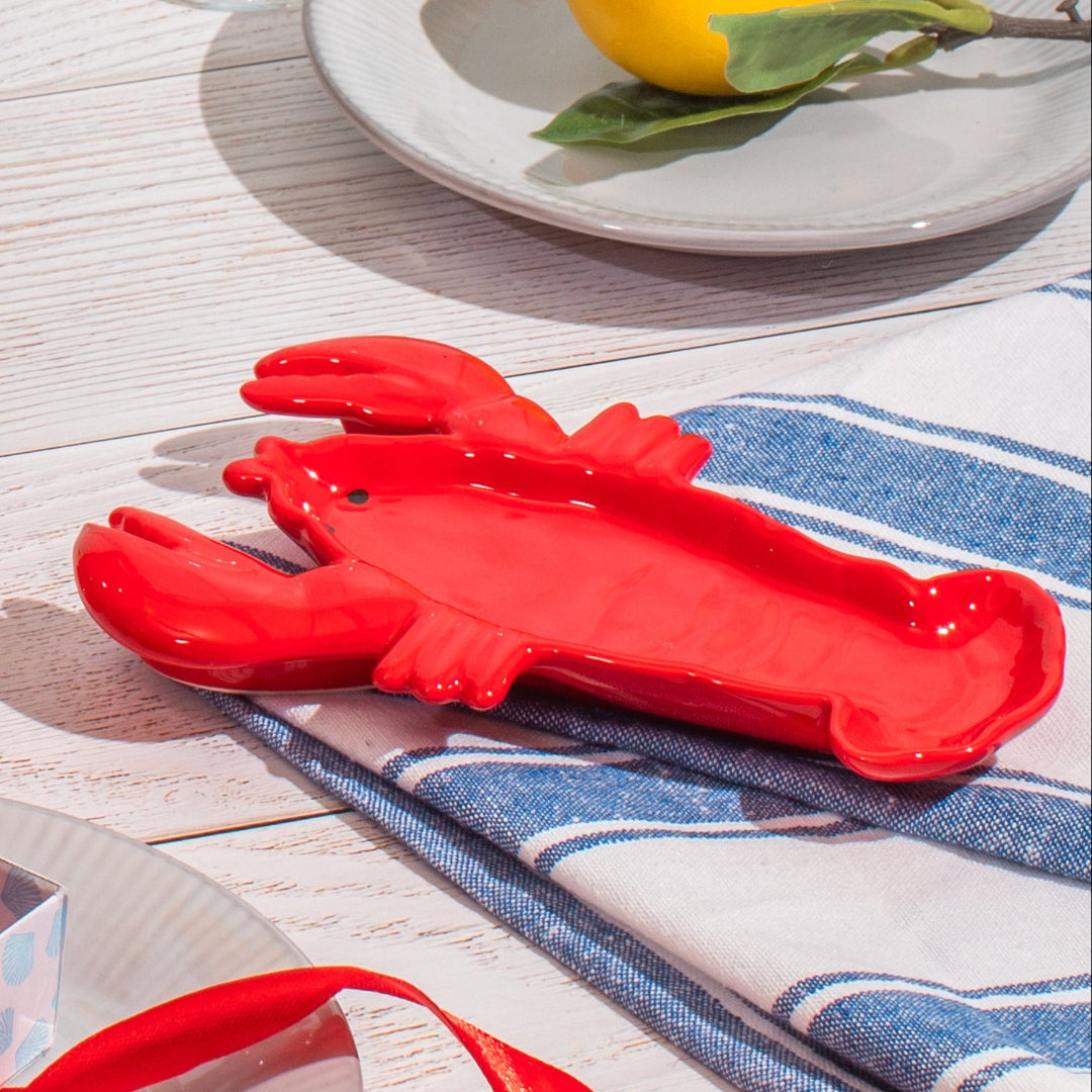 Alhajero en forma de langosta roja sobre una mesa y paño azul. 