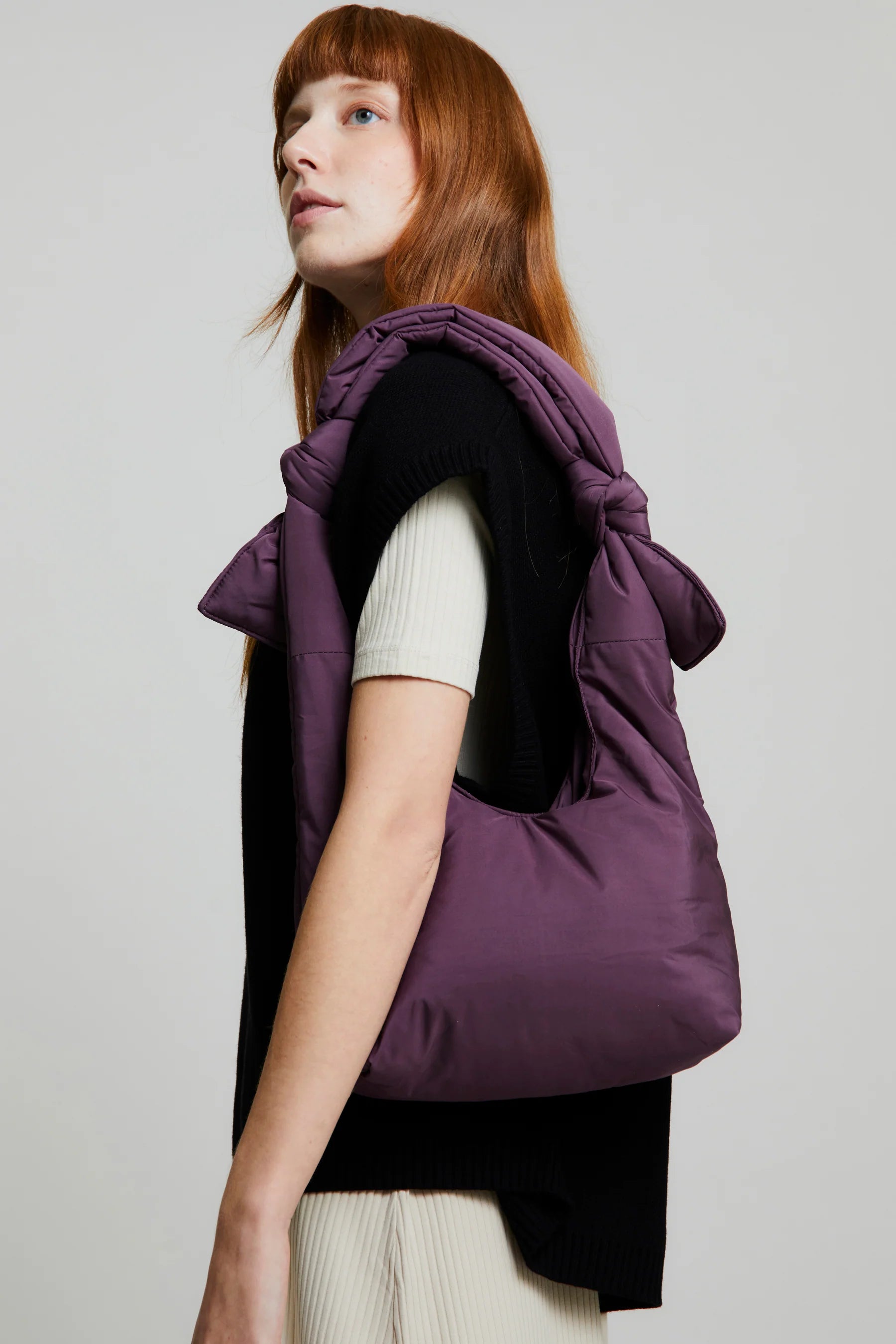 Mujer con el bolso Biwa color morado ciruela acolchado con asa ajustable con dos nudos hecho de botellas de plástico recicladas
