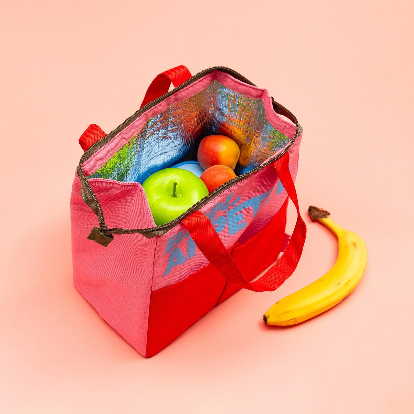 Bolsa isotérmica para llevar el almuerzo con cremallera abierta con tupper y fruta