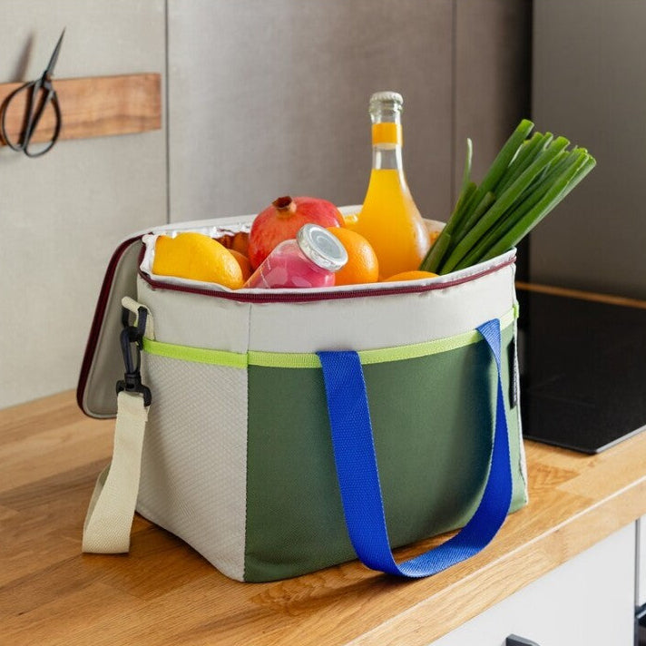 Bolsa térmica Bruno de la marca Remember en tonos verdes con detalles azules y amarillos rellena de frutas, verduras y bebidas.