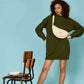 Mujer con vestido de punto verde y el bolso riñonera de pana beige de la marca Hindbag con forma de media luna