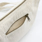 Detalle del bolsillo trasero con cremallera del bolso riñonera de pana beige de la marca Hindbag con forma de media luna