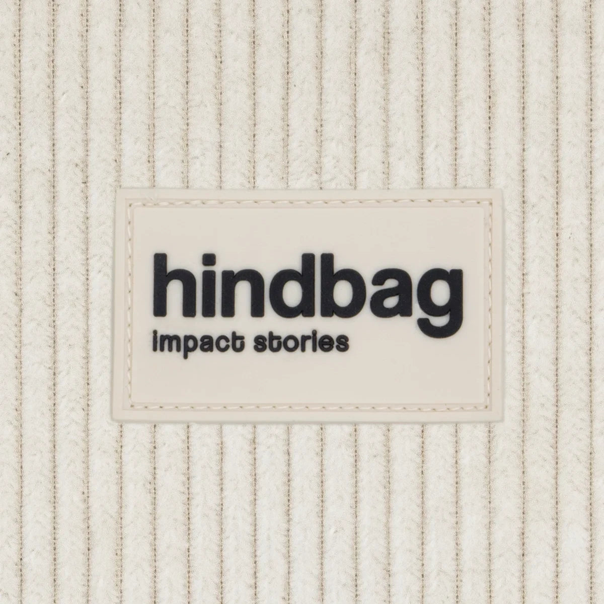 Primer plano de la marca del bolso riñonera de pana beige de la marca Hindbag con forma de media luna 