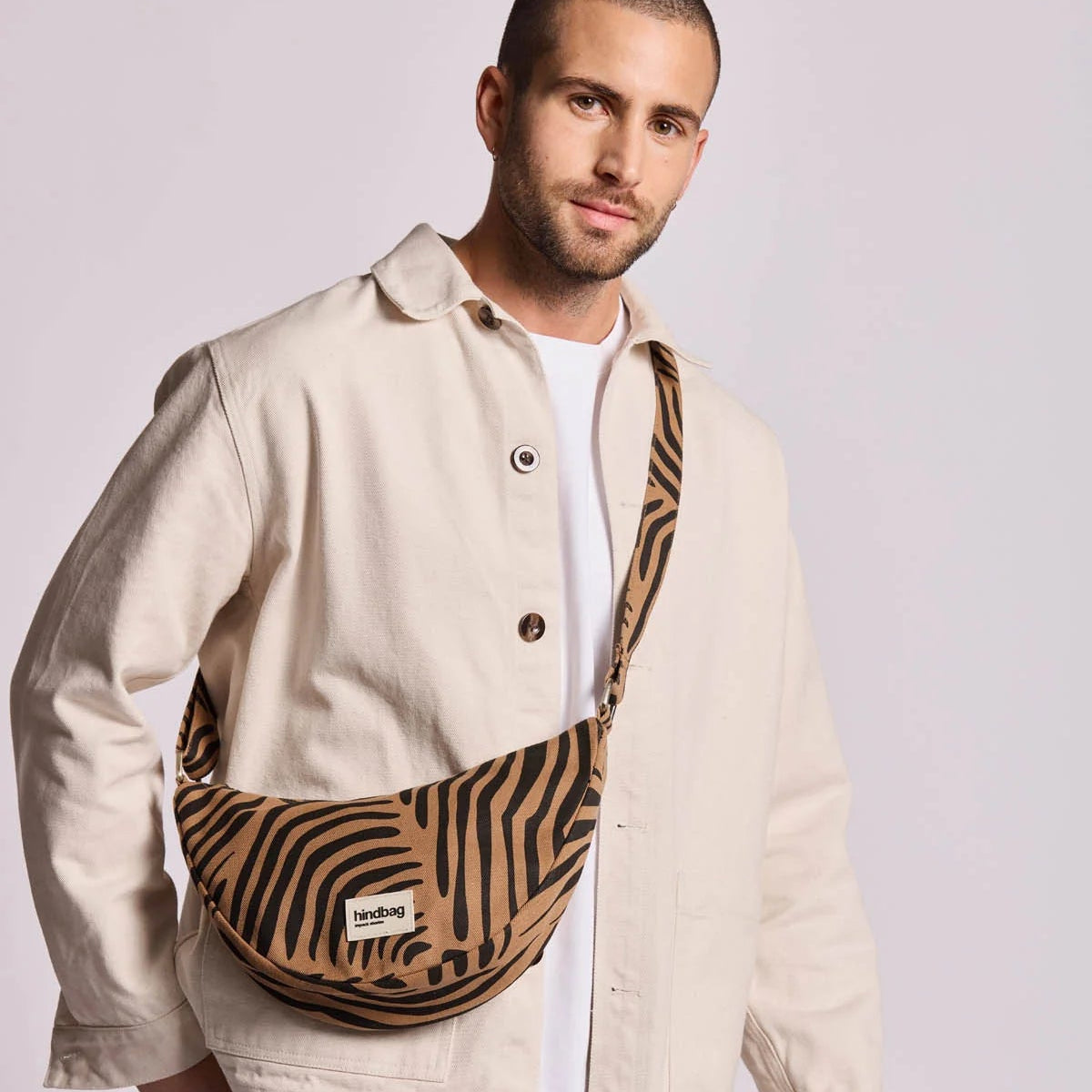 Chico con el bolso de media luna de Hindbag en color marrón y estampado de cebra colgado del hombro