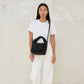 Modelo de frente con el mini bolso acolchado Ani de Lefrik en negro en bandolera combinado con pantalones y camiseta blancos