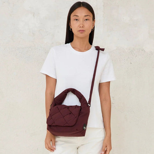 Modelo llevando el mini bolso acolchado Ani de Lefrik en burdeos cruzado al cuerpo, vista frontal completa