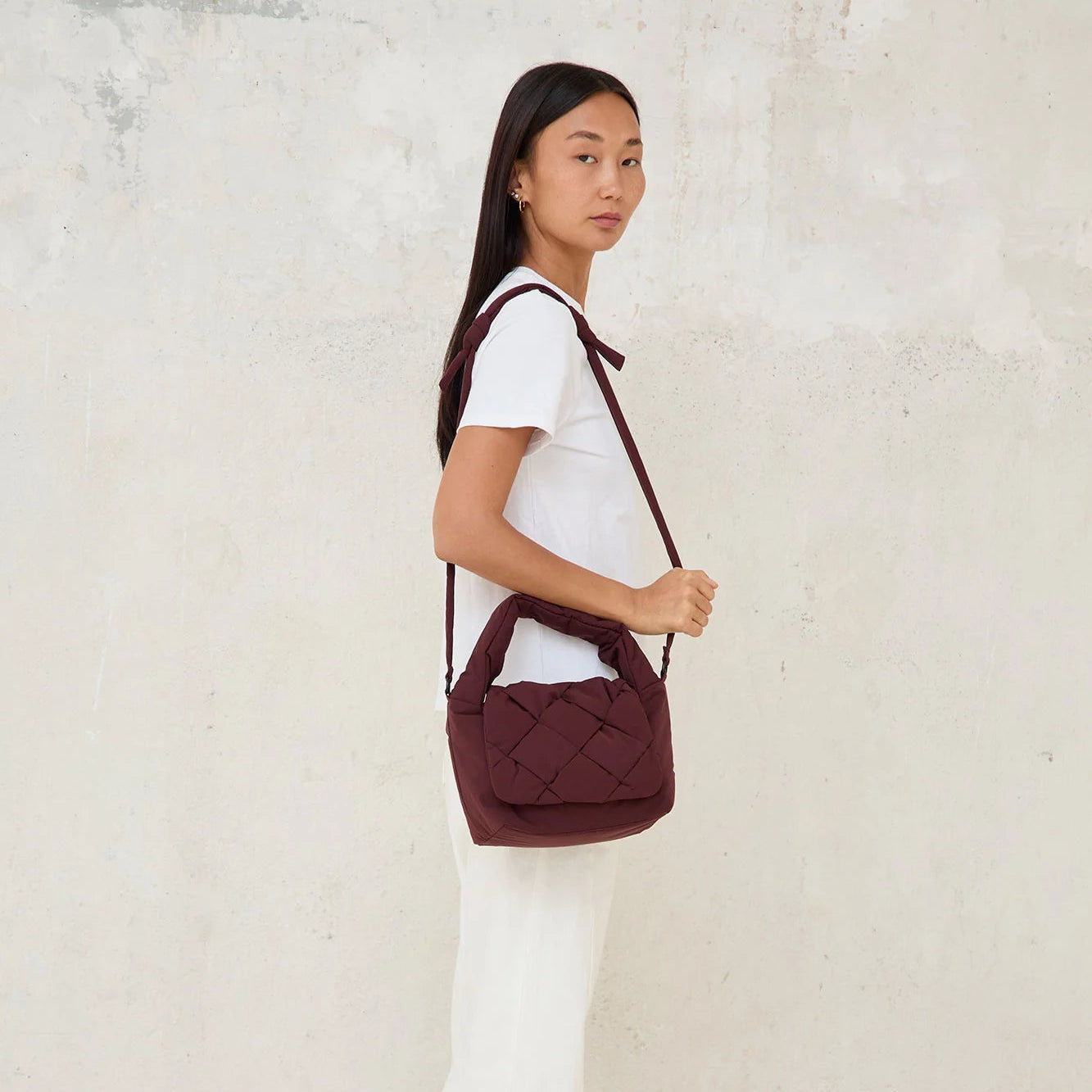 Modelo de perfil con el mini bolso acolchado Ani de Lefrik en burdeos en bandolera, vista lateral