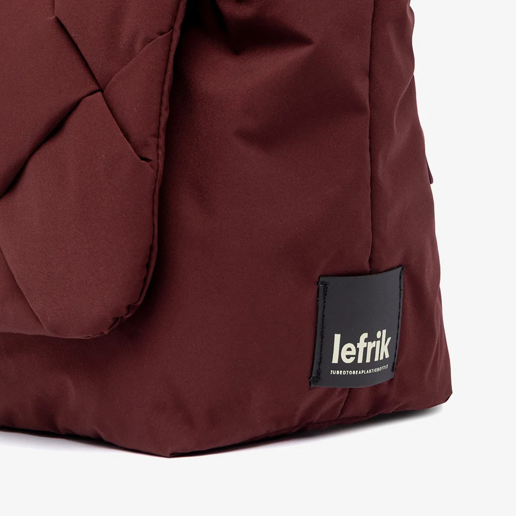 Detalle de la etiqueta Lefrik sobre el tejido acolchado en color burdeos del bolso Ani mini