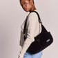 Mujer de perfil con bolso de pana color negro con dos bolsillos frontales con cremallera y correa ajustable de la marca francesa Hindbag 