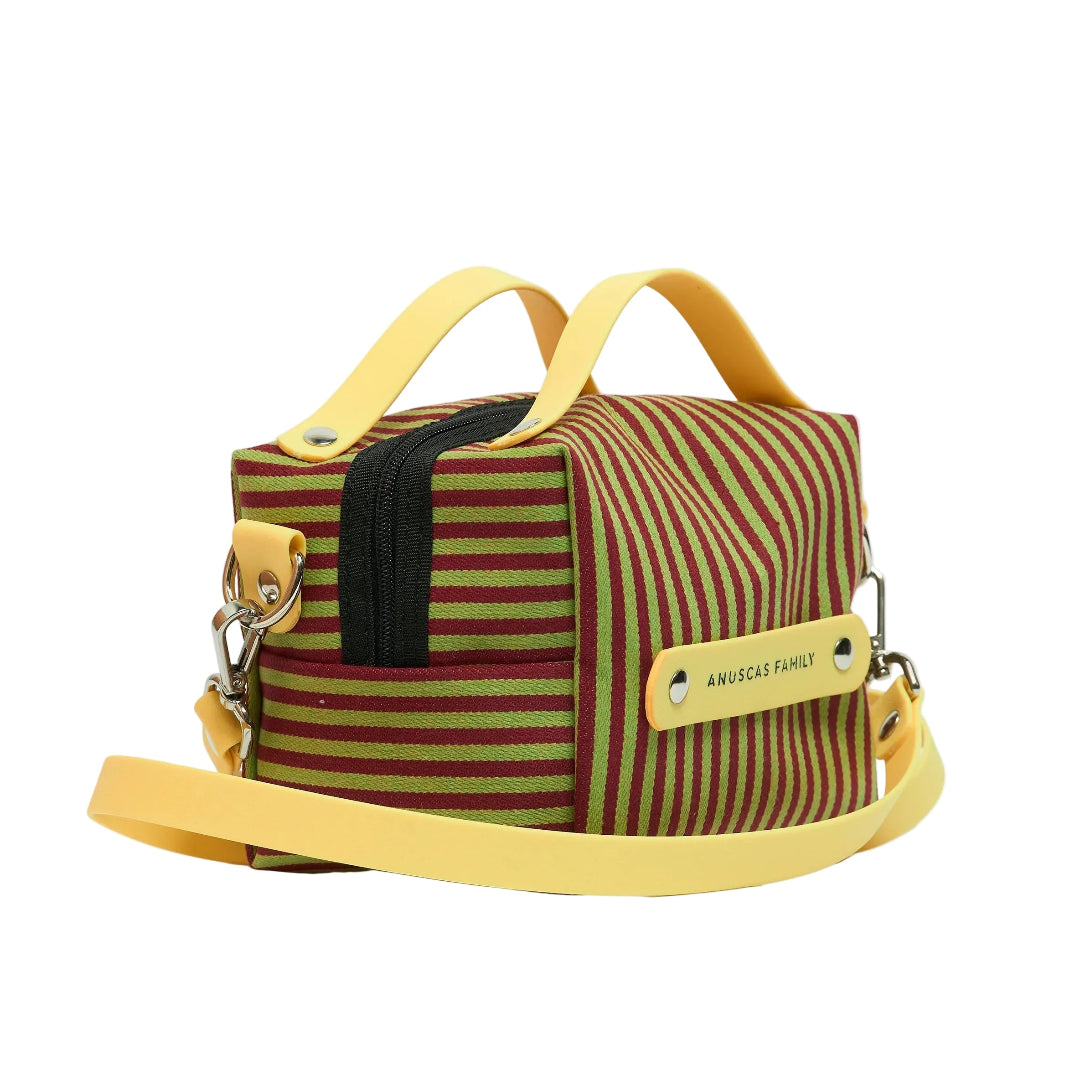 Vista lateral del bolso pequeño con forma de caja y cremallera a rayas verticales burdeos y verdes con correa y asa amarillas de la marca de Sevilla Anuscas Family