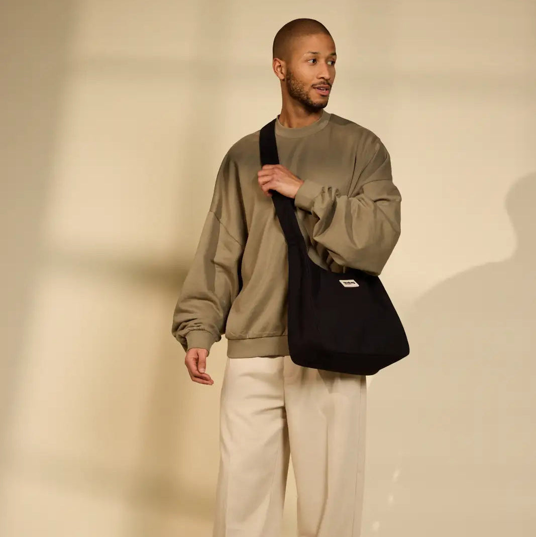 Chico con sudadera ocre y el bolso cruzado negro de la marca francesa hindbag